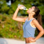 женщина пьет воду во время пробежки